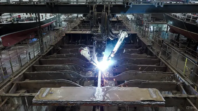 Welding robot tracing a seam on a ship hull in a dry dock